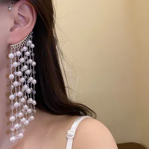Detailed view of elegant white pearl tassel ear cuff worn on a model's ear.