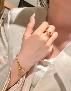 Detail of ornate golden snake-style bracelet and heart-shaped red gemstone ring set