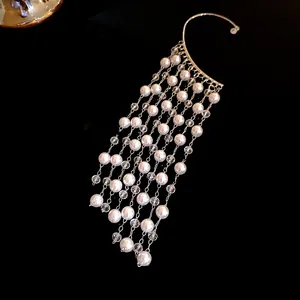 Close-up of elegant vintage pearl and crystal tassel ear cuff on deep black background