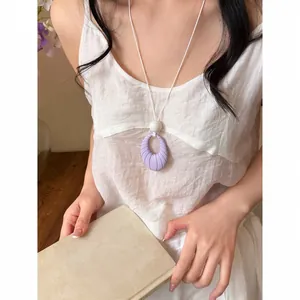 Close-up of lavender oval pendant necklace with ribbed texture worn by a model