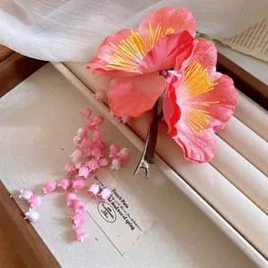 Pink fabric flower hair clip with lily-of-the-valley tassel in a vintage jewelry box