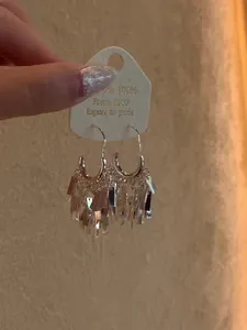 Detailed macro view showing silver sequin fringe tassel hoop earrings on a jewelry card
