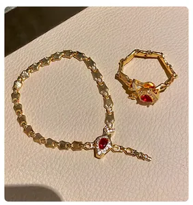 Close-up of vintage gold snake chain bracelet and red gemstone ring on leather texture