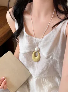 Elegant long necklace featuring a textured yellowish-green oval pendant worn by a model