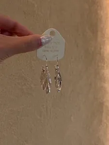 Close-up detail shot showing the elegant silver sequin tassel earrings on white display card