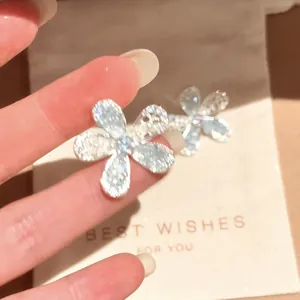 Close-up view of a sparkly glass flower stud earring featuring delicate rhinestone details.
