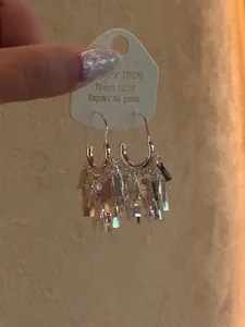 Detailed view of elegant silver sequin tassel earrings held against a neutral wall