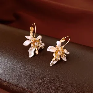 Vue détaillée de boucles d'oreilles fleurs vintage avec émail blanc et zircons