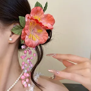 Detail view of a pink fabric flower hair clip with elegant hanging floral tassels on model