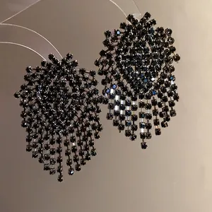 Detailed close-up of luxurious geometric black rhinestone tassel earrings design.