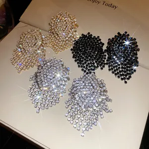 Close-up detail of luxury rhinestone geometric tassel earrings in silver, gold and black.