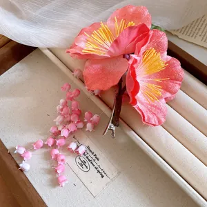 Detailed view of pink fabric flower hair clip with elegant dangling flower tassels