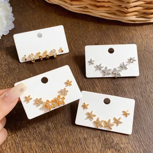 Close-up of zircon starfish earring sets and gold hoops on white display cards