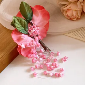 Detailed view of pink fabric flower hair clip with hanging lily of the valley tassels