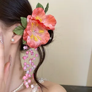Detailed view of pink fabric floral hair clip with bell-flower tassels on model