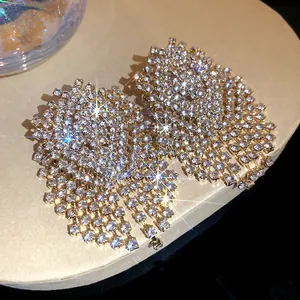Detailed view of sparkling geometric rhinestone tassel earrings with silver needles.