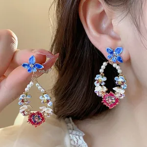Boucles d'oreilles fleuries dorées 14 carats avec perles et détails en émail coloré.