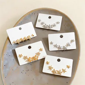 Macro view of gold and silver zircon starfish earring sets on white display cards