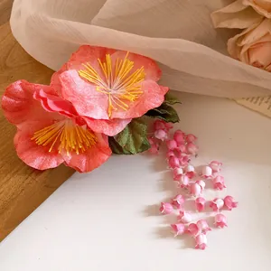 Close-up of a pink fabric flower hair clip with delicate lily of the valley tassels