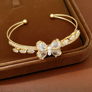 Close-up of gold butterfly cuff bracelet with sparkling zircon stones and tiny pearls.