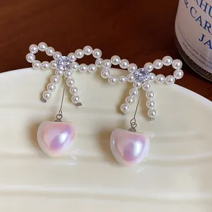 Detailed close-up of elegant bow heart pearl earrings featuring sparkling zircon centerpieces