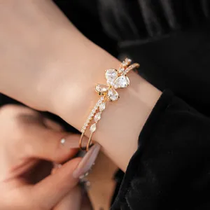 Detailed view of an elegant gold-tone zircon butterfly open bangle worn on a wrist.
