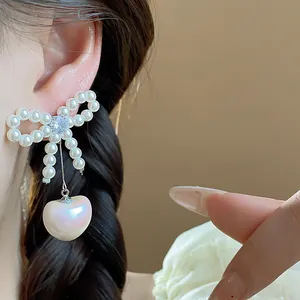 Close-up of elegant bow-knot pearl earrings with a heart-shaped pearl drop