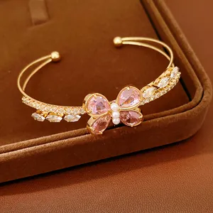 Close-up of gold-plated butterfly bangle with pink zircons and pearls on brown velvet tray