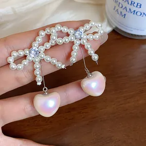 Detailed close-up of French style bow earrings featuring iridescent heart pearls