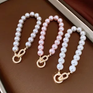 Detail of white and pink pearl bracelets featuring elegant zircon-studded interlocking clasps.