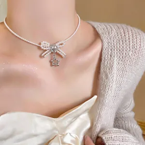 Primo piano di collana girocollo di perle con fiocco di zirconi e ciondolo a stella