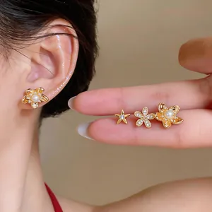 Detailed view of gold-plated starfish and flower earrings set with zircon and pearls