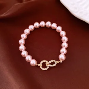 Close-up detail of a pink pearl beaded bracelet featuring an elegant gold-toned zircon clasp
