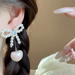 Close-up detail of French style bow-knot earrings featuring zircon and heart pearl drop