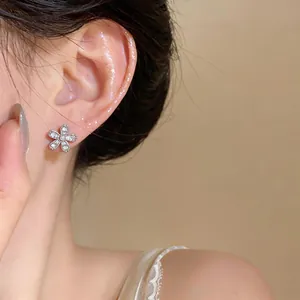Close-up detail of a delicate silver flower stud earring with sparkling zircon stones
