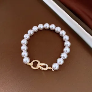 Detail view of elegant pearl bracelet featuring a gold-plated zircon interlocking clasp