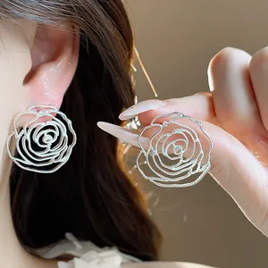 Dettaglio di orecchini a lobo a forma di rosa traforata in argento dal design elegante