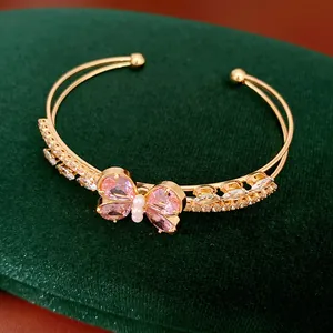 Detailed view of pink zircon butterfly centerpiece on a gold-tone double-layered cuff bracelet.