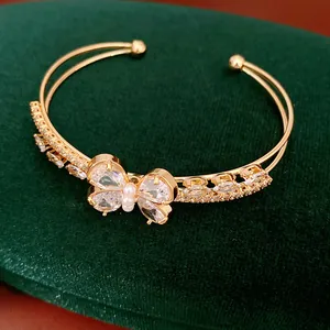 Macro view of a luxurious double-layered golden cuff bracelet featuring a zircon butterfly motif.