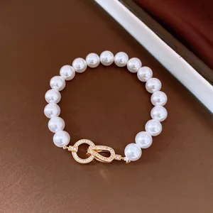 Close-up of elegant pearl bracelet with gold zircon-studded interlocking clasp