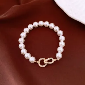Close-up of pearl bracelet featuring a zircon-encrusted gold-tone infinity clasp.