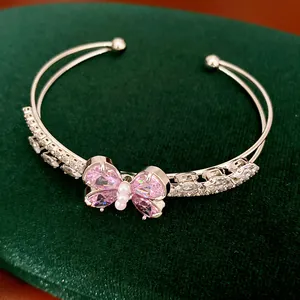Detailed view of silver-toned bangle featuring a pink zircon butterfly and clear stones
