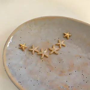 Close-up of gold starfish stud earring set with sparkling cubic zirconia on ceramic