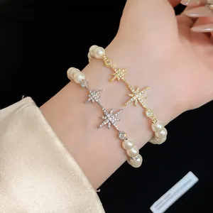 Detailed view of elegant pearl bracelets with sparkling zircon star charms worn on wrist.