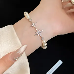 Close-up of elegant pearl bracelet featuring sparkling zircon star charms on wrist.