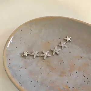 Detailed view of silver-toned zircon starfish stud earrings set on a ceramic dish