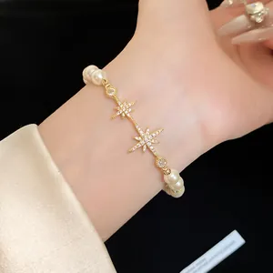 Detailed shot of 18k gold-plated star charm bracelet with zircon and pearls on wrist