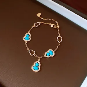 Vista dettagliata di un bracciale in oro con ciondoli a zucca, turchese e zirconi.
