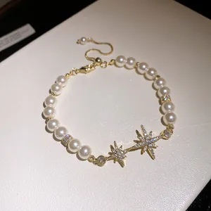 Detail of 18k gold plated star charm and lustrous pearl bracelet with zircon accents