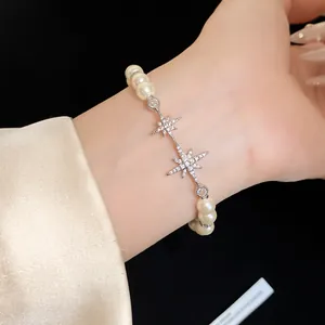 Close-up of elegant 18k gold plated pearl bracelet with zircon starburst charms on wrist